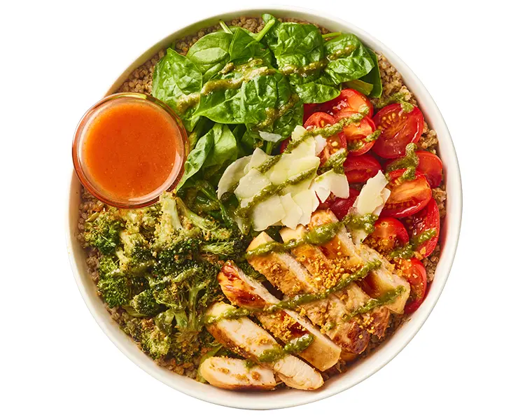 Freshii Chicken Pesto Parmesan bowl with grilled chicken, quinoa, spinach, grape tomatoes, broccoli, parmesan and pesto vinaigrette, served with hot sauce