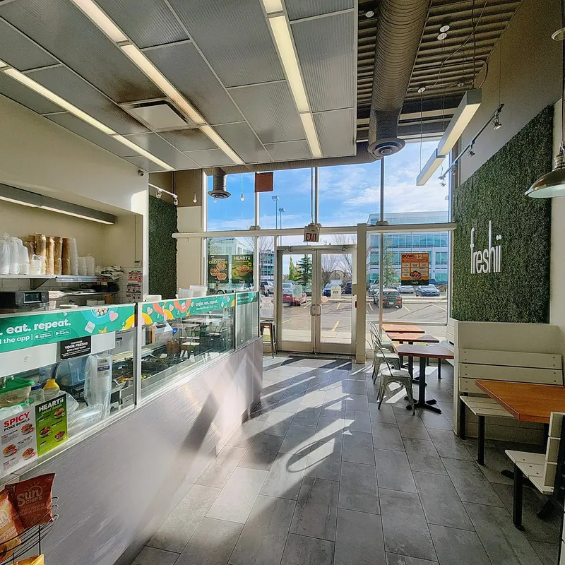 Bright dining room and order counter at Freshii Sundance, a healthy restaurant in Sundance, SE Calgary, with dine-in seating by the front windows.